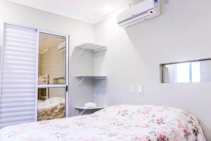 a white bedroom with a bed and a window at Casas aconchegantes in São Sebastião