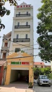 un edificio alto con un coche aparcado delante de él en SƠN HÀ Motel en Hai Phong