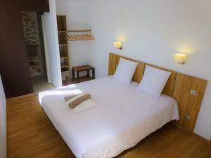 Schlafzimmer mit einem weißen Bett mit einem Kopfteil aus Holz in der Unterkunft L'Accent d'ici in Le Somail