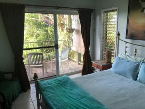 - une chambre avec un lit et une porte coulissante en verre dans l'établissement Mission Beach Escape BnB, à South Mission Beach