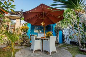 a table and chairs under an umbrella in a garden at Svaha Private Villas Ceningan in Nusa Lembongan