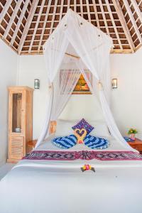 a bedroom with a white bed with a canopy at Svaha Private Villas Ceningan in Nusa Lembongan