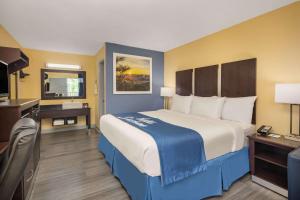 una camera d'albergo con un grande letto e una scrivania di Days Inn by Wyndham Muscle Shoals a Muscle Shoals