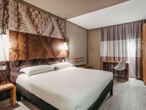 una camera d'albergo con un grande letto e una scrivania di Ibis Mohammedia a Mohammedia