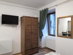 a room with a tv and a cabinet and a mirror at Sara House in Bistriţa