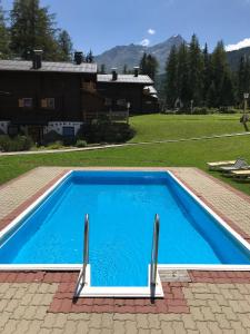 a blue swimming pool in a yard with a house at Pension Waldesruh in Sölden