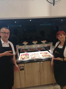 two people standing in front of a buffet of food at Hotel Scala d'Oro in Vodice