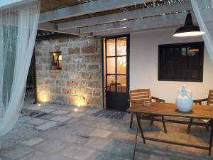 un patio con una mesa de madera y una pared de piedra en Casetta Vacanza in Campagna, en Aradeo