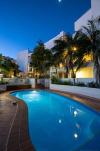 a swimming pool in front of a building at night at Bay Royal Apartments in Byron Bay