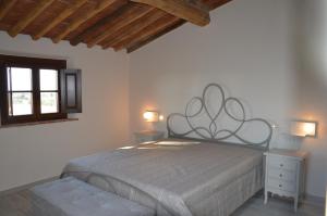 a bedroom with a bed and two tables and a window at Moraiolo Podere le Bozze con piscina WI-FI in Castagneto Carducci