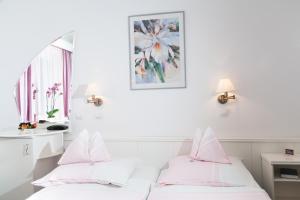 two beds in a room with white walls and pink pillows at Fábián Panzió in Kecskemét