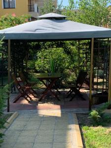 a gazebo with a picnic table and an umbrella at Lilia Guest House in Nesebar