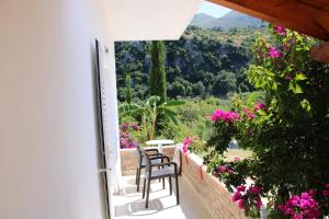 two chairs sitting on a porch with flowers at Penelope's Rooms in Dhërmi