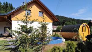 a house with a tree and a tub in a yard at Chalupy Vichrovky in Bělá pod Pradědem