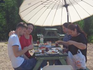 eine Gruppe von Menschen, die an einem Picknicktisch unter einem Schirm sitzen in der Unterkunft Farmhill in Yeniceköy