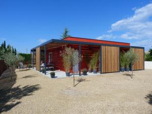 un petit bâtiment rouge avec des plantes en pot dans l'établissement Les Lodges - Villa avec spa privatif, à Valensole