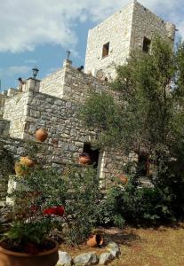 un edificio de piedra con plantas delante de él en Charouda Stone Tower, en Pyrgos Dirou