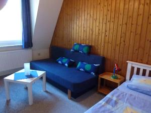a living room with a blue couch and a bed at Ehemaliges Waldkurhaus Drangstedt in Drangstedt