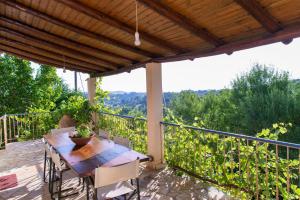 a patio with a wooden table and chairs on a balcony at Villa with private garden in Kréstena