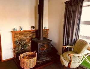 a living room with a wood stove and a chair at Harbour Side Views in Dunedin