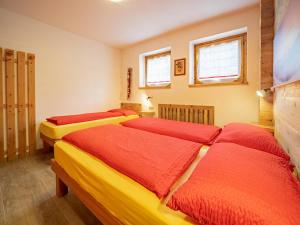 Zimmer mit 3 Betten mit roter und gelber Bettwäsche in der Unterkunft Leveron Apartments in Livigno