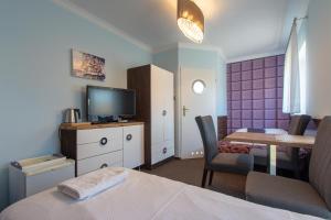 Schlafzimmer mit einem Bett, einem Tisch und einem TV in der Unterkunft Villa 33 Blisko Plaży in Sopot