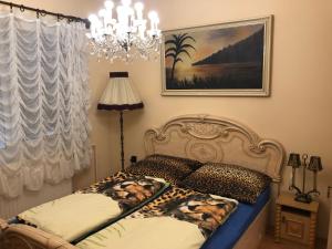 a bedroom with a bed with leopard pillows and a chandelier at Balatonalmádi Apartmanház in Balatonalmádi +32 photos