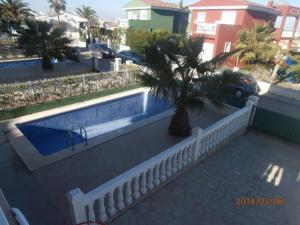 a white fence with a palm tree next to a swimming pool at Precioso chalet con piscina privada in Peñíscola