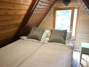 a bed with two pillows in a room with a window at Erdő Kapitánya Vendégház in Tata