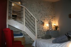 a bedroom with a staircase and a bed with a red chair at Le domaine des rouges queues in Châteaudouble