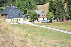 ein Bauernhof mit zwei Häusern und einer Straße in der Unterkunft Ferienwohnung Waldmühle in Saupsdorf