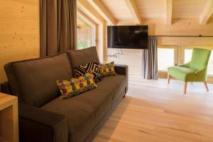 a living room with a brown couch and a green chair at Appartement Omeshorn anno 1593 in Lech am Arlberg