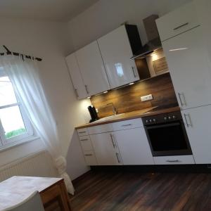 a kitchen with white cabinets and a sink and a window at Ferienwohnung WohlfühlEckerl in Tittmoning +16 photos