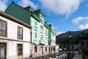 un edificio verde y blanco al lado de una calle en Alojamiento Calzada Romana, en Belmonte de Miranda