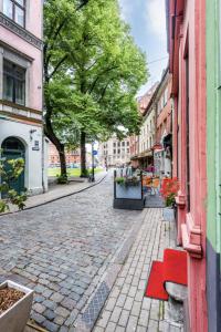 a cobblestone street in a city with a red bench at Doma square apartment 2, in the heart of Old town in Riga
