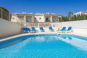 una piscina con sillas azules y una casa en D_Loft Ocean, en Albufeira