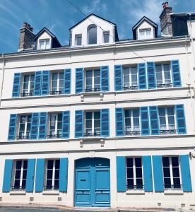 - un bâtiment blanc avec des portes et des fenêtres bleues dans l'établissement Maison d'architecte en plein cœur d'Honfleur avec bain nordique, à Honfleur