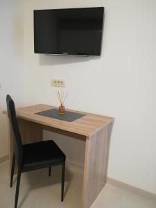 a wooden table with a chair and a television on a wall at Apartman Ana in Porat