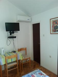 Pokój ze stołem i telewizorem na ścianie w obiekcie Guesthouse Lidija w mieście Kukljica