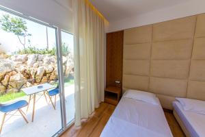 a room with a bed and a table and a window at Inada Hotel Ksamil in Ksamil