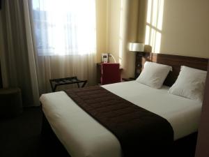 a bedroom with a large bed with a window at Hotel Vauban in Besançon