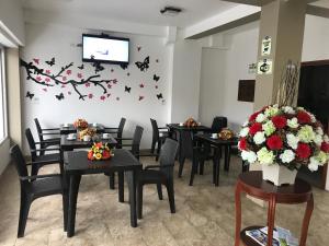 a dining room with tables and chairs and a tv at Hotel Seny in Ambato