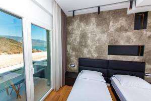 a bedroom with a bed and a glass wall at Inada Hotel Ksamil in Ksamil