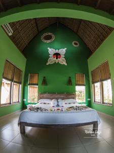 a bedroom with a green wall with a bed in it at Kuda Laut Bungalows & Diving in Pemuteran