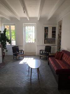 ein Wohnzimmer mit einem Sofa, Stühlen und einem Tisch in der Unterkunft Tilleuls et Bambous in Saint-Sauveur-dʼAunis