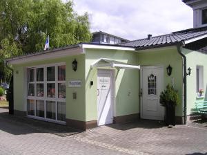 mały zielony i biały budynek z drzwiami w obiekcie Pension Dünenhaus w mieście Zempin