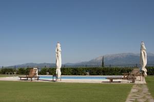 two benches and umbrellas next to a swimming pool at Villa Anna in Nafpaktos
