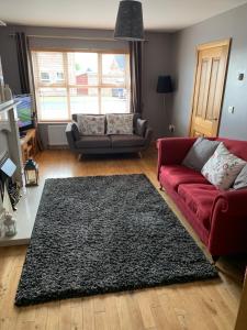 ein Wohnzimmer mit einem roten Sofa und einem schwarzen Teppich in der Unterkunft Portstewart - holiday let in Portstewart