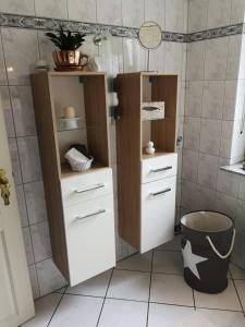 a bathroom with white cabinets and a trash can at Ferienwohnung Menden in Menden