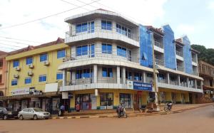 ein Gebäude auf einer Straße mit davor geparkt in der Unterkunft Hotel Dot Com Entebbe in Entebbe